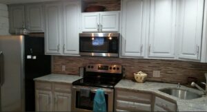 Granite kitchen island and counters with stainless steel appliances and tile backsplash