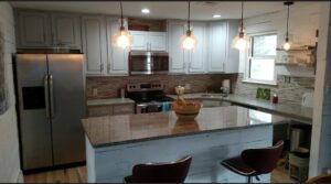 Granite kitchen island and counters with stainless steel appliances and tile backsplash