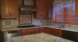 Granite kitchen island and counters with stainless steel appliances and tile backsplash