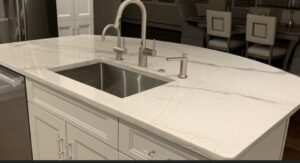 Elegant kitchen island featuring a sleek stainless steel sink, modern brushed nickel fixtures, and a polished white marble countertop with subtle gray veining, creating a luxurious and contemporary centerpiece.